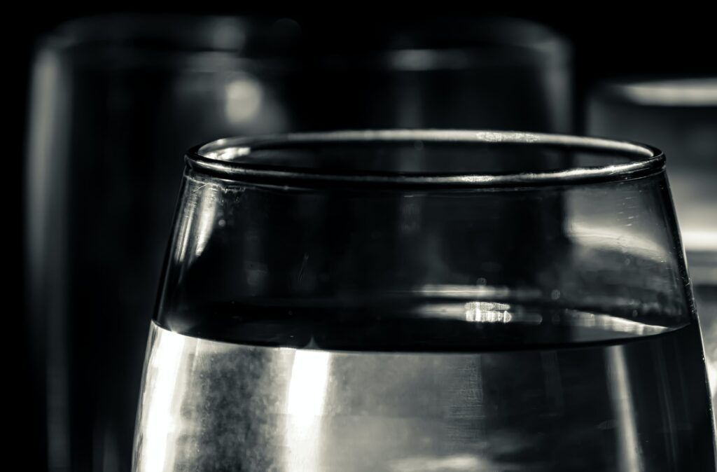 Een close-up van een glas tijdens een diner in het donker Ctaste. 