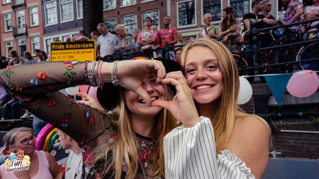 Two girls forming a hearth with their hands during the Canal Pride.